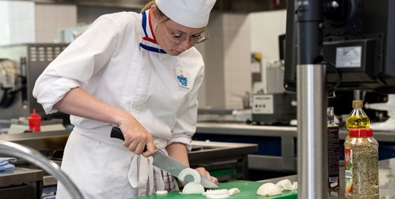 Vrouw die eten snijdt in een keuken van een horecagelegenheid