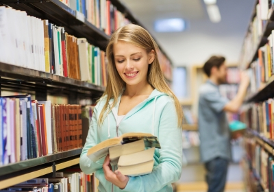 Vrouw leest boek in bibliotheek